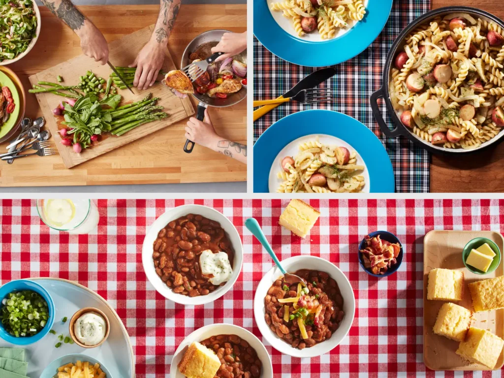 Hands prepare asparagus and salad on a cutting board; pasta and beans with cornbread are served on colorful dishes.